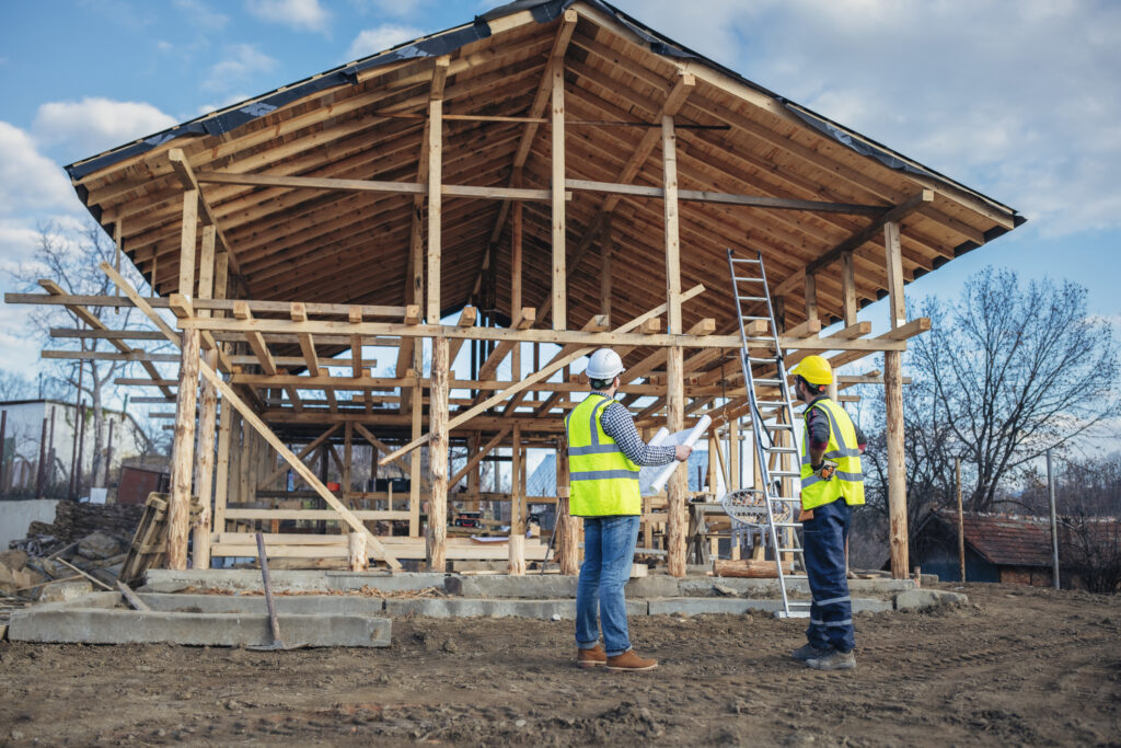 Residential construction contractors discussing wooden house framing